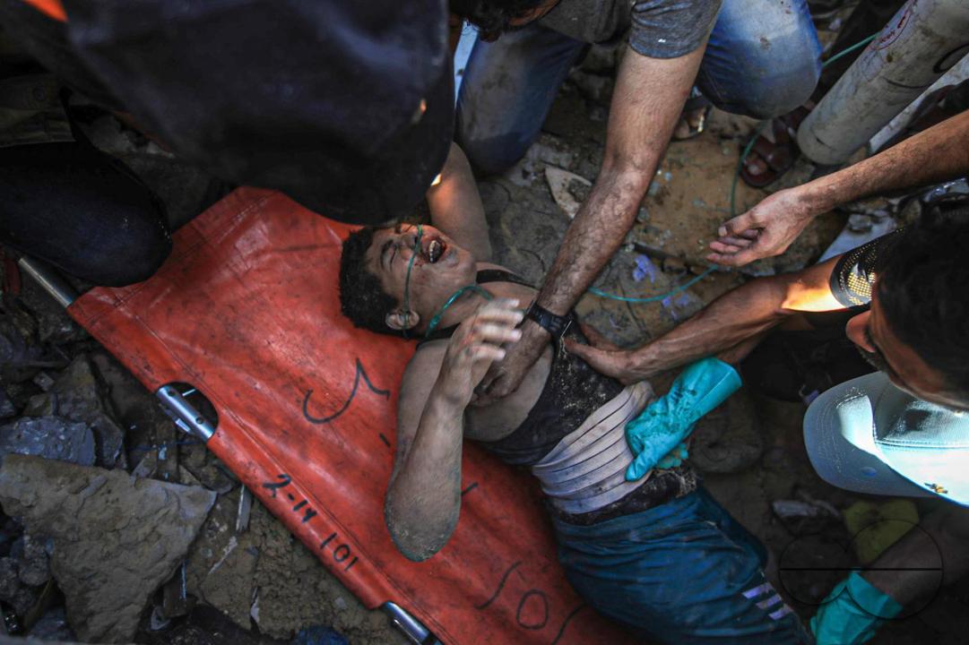 The Palestinian Civil Defense is trying to get a Palestinian child out of the rubble of his house, which was destroyed by Israeli planes in Khanounes, southern Gaza Strip