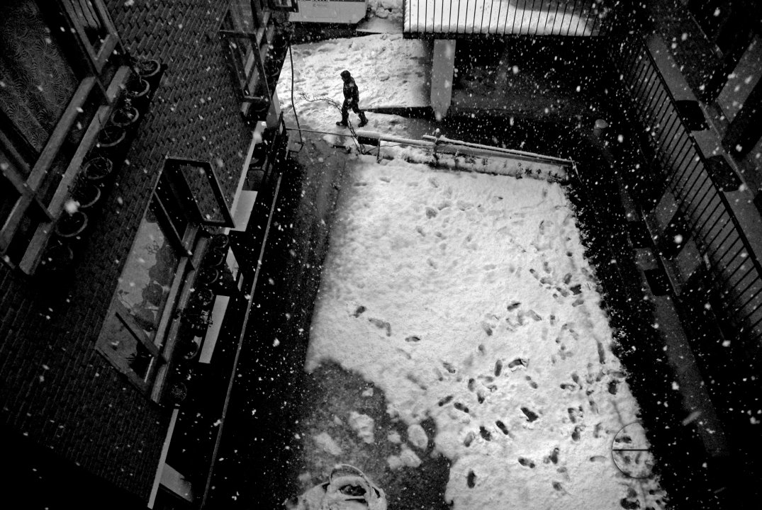 A worker in a hotel in Srinagar walks across the courtyard as it snows.