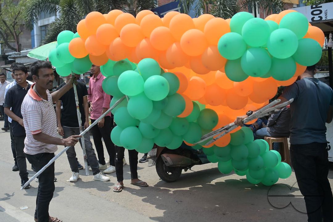 Supporters of the BJP are seen decorating balloons in the party's colours at a rally featuring Tripura Chief Minister Manik Saha, former CM and BJP candidate Biplab Kumar Deb, and Kriti Singh, alongside other leaders, during an election campaign rally in