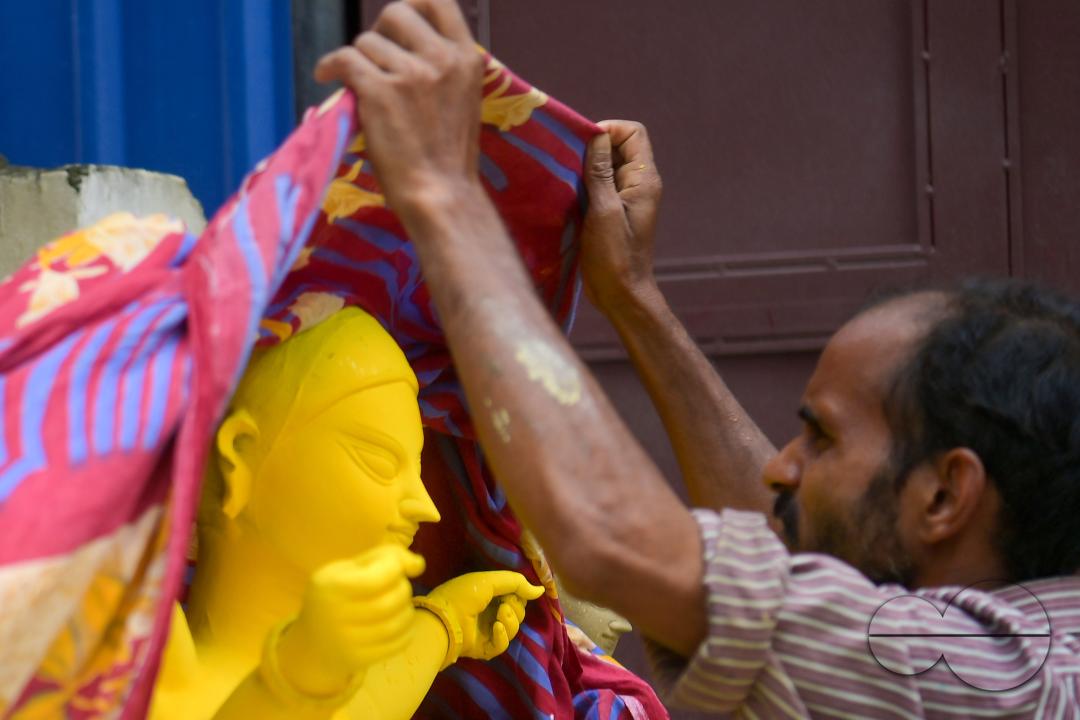 An idol maker is covering an idol of the Mother Goddess Durga during a rainstorm in a studio, ahead of the Durga Puja festival in Agartala, Tripura, India.