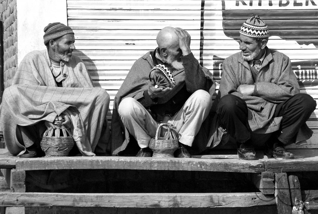 Three Kashmiri men talk by the side of the road.