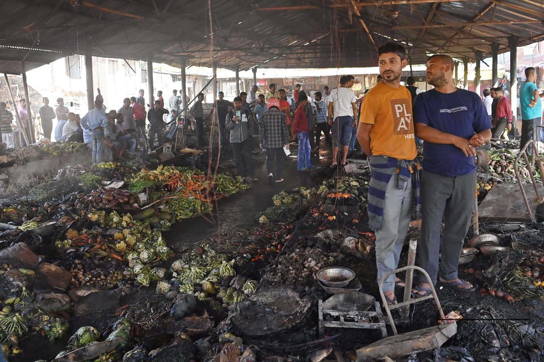 Shop owners and vendors are seen in front of their burnt shops and vegetables stalls in Battala market, the second biggest market in Tripura