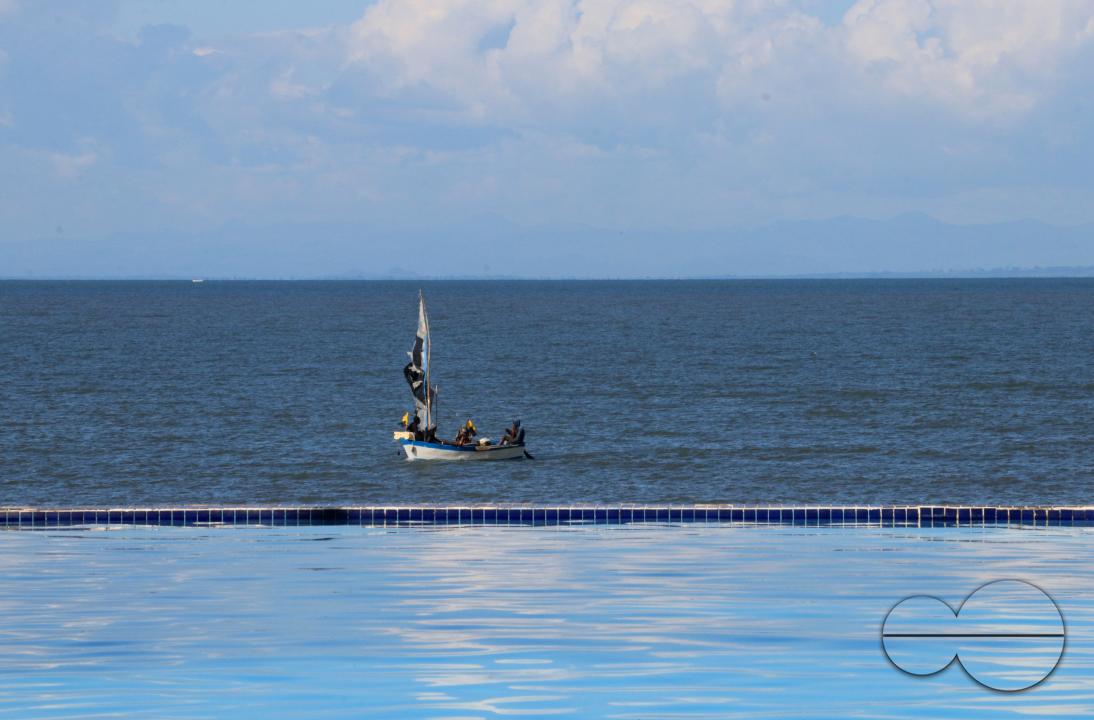 A lone fishing boat is seen in the bakground of an infinity pool at a local resort in Salima, Malawi.