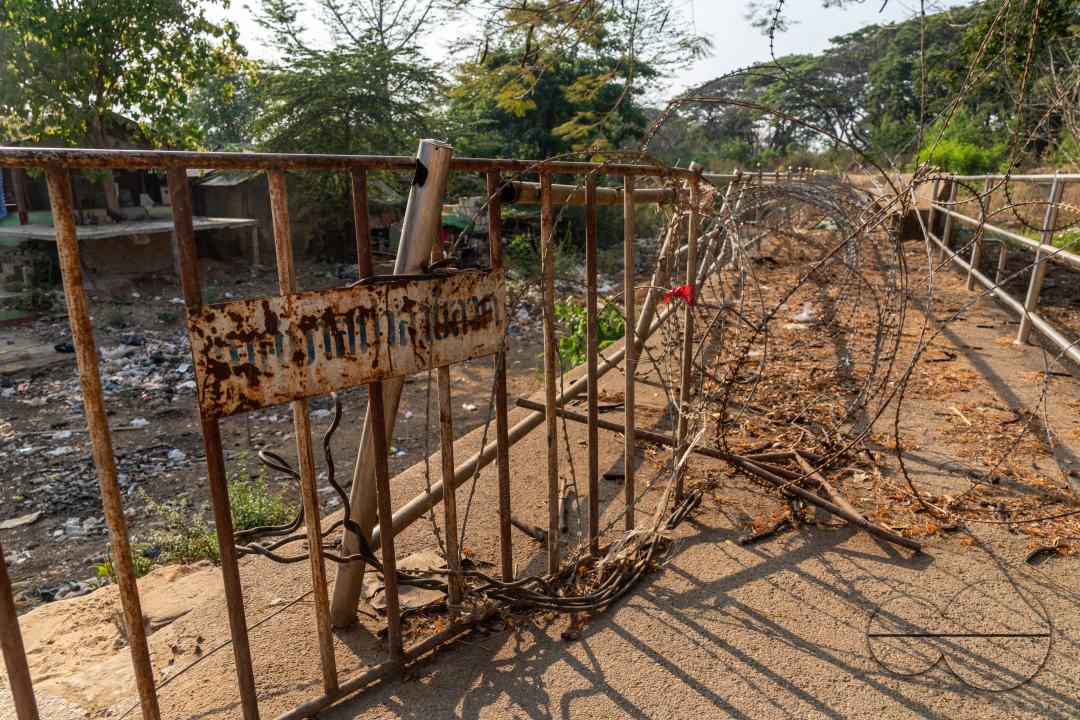 Visitors, traders and illegal Burmese immigrants walk by barbed wire at the Thai side of the Thailand - Myanmar border at Mae Sot, Thailand.