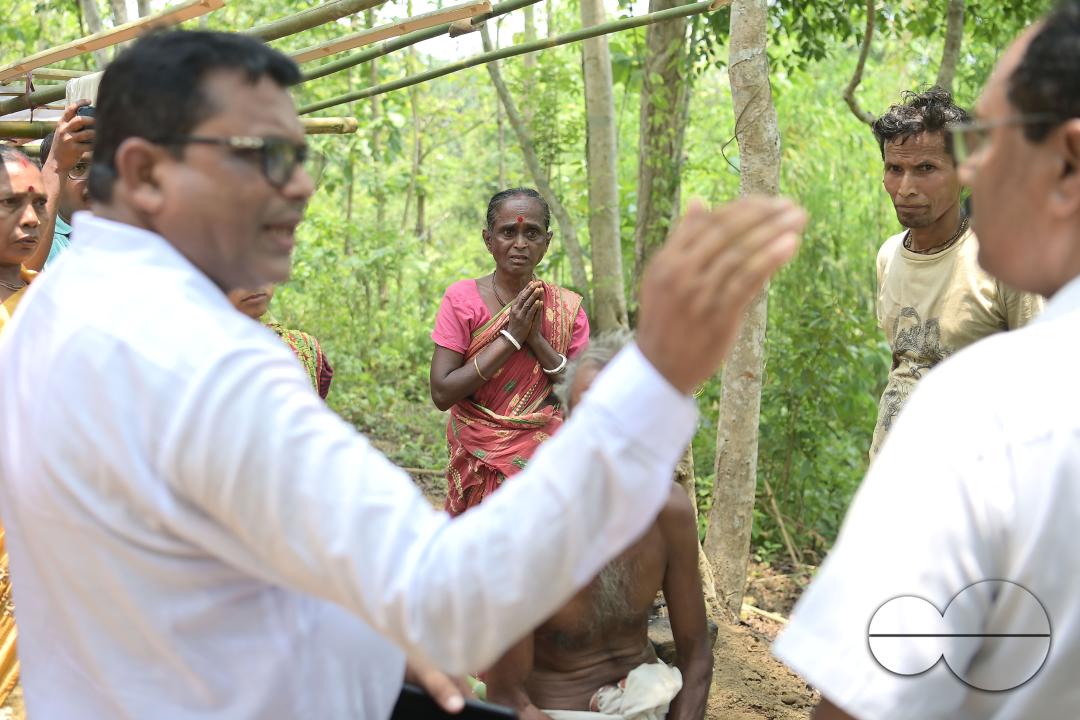 An elderly woman is crying in front of local MLAS officials at her makeshift tent at the Panisagar's reserve forest
