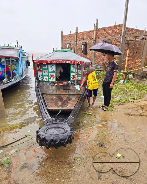 Passengers embarking and disembarking, in the tropical rain, from country launches which are berthed at the shore of Dingapotha, Mohonganj âhaorâ (a large body of wetland formed by river and rain water, famous as a fishing area)