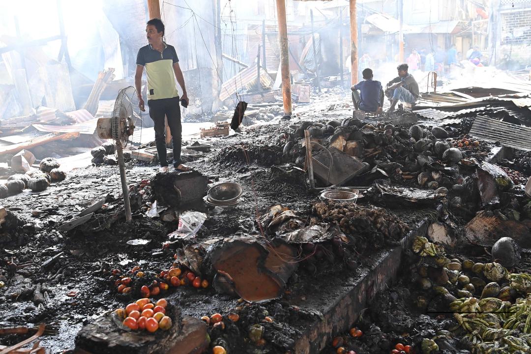 Shop owners and vendors are seen in front of their burnt shops and vegetables stalls in Battala market, the second biggest market in Tripura