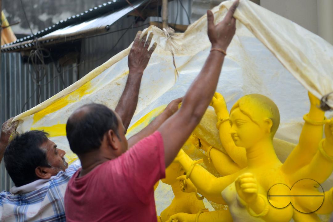 Idol makers are covering an idol of the Mother Goddess Durga during a rainstorm in a studio, ahead of the Durga Puja festival in Agartala, Tripura, India.