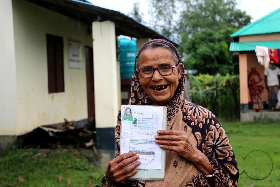Portrait of a rural Bangladeshi woman showing her accommodation and old age allowances which are donated by the government