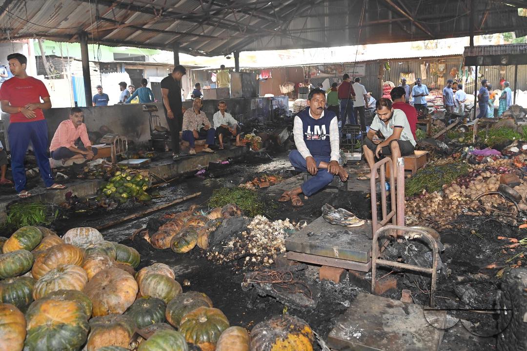 Shop owners and vendors are seen in front of their burnt shops and vegetables stalls in Battala market, the second biggest market in Tripura