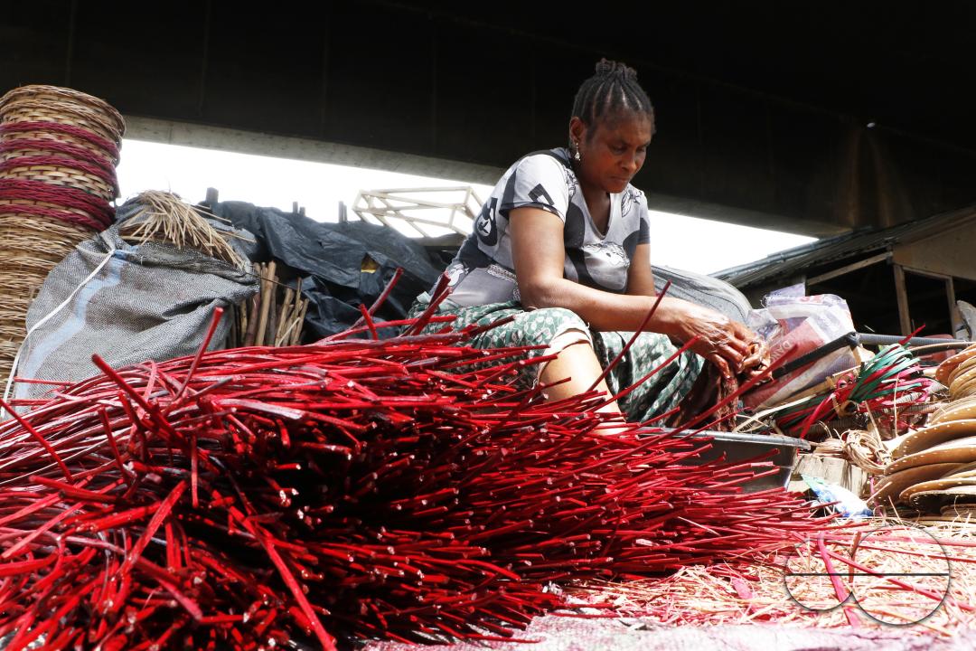 A woman processes a wine colored cane wood for weaving at Nigeria's largest cane 'village' at Mende in the Maryland District of Lagos