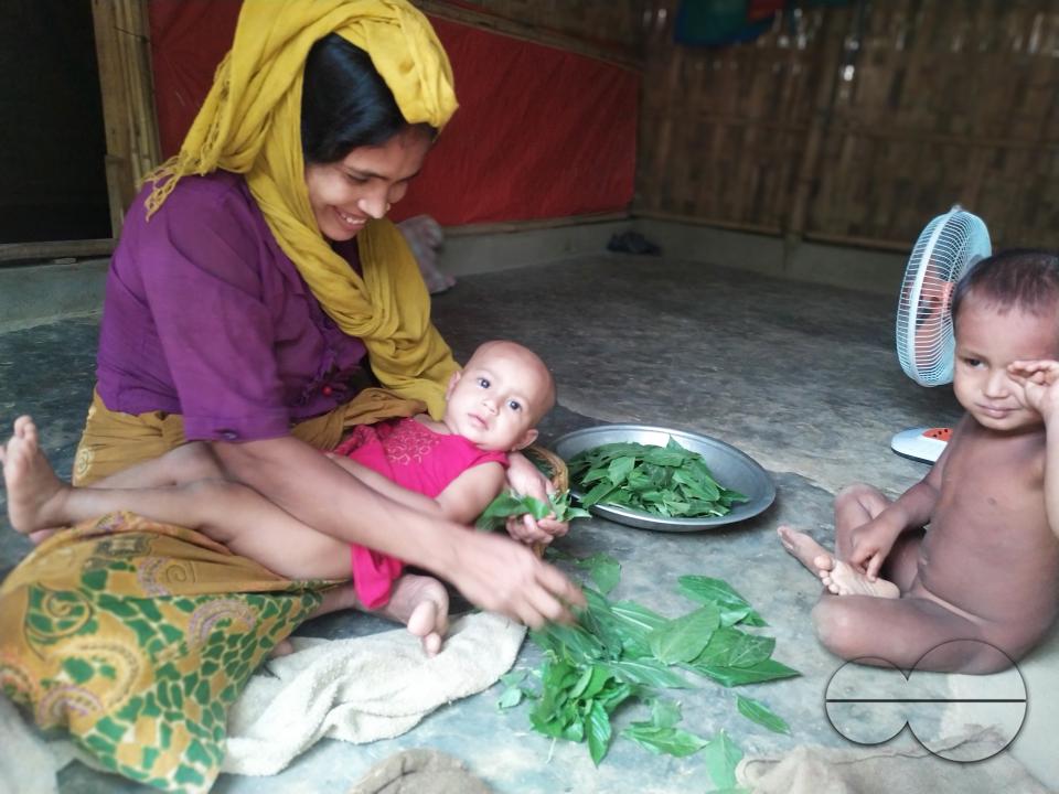 A mother cooking with her two kids nearby at the Balukhali refugee camp