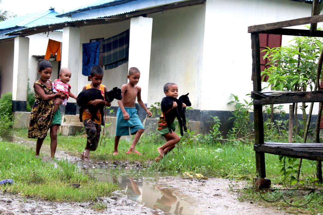Rural Bangladeshi children happily playing in the neighborhood with goats
