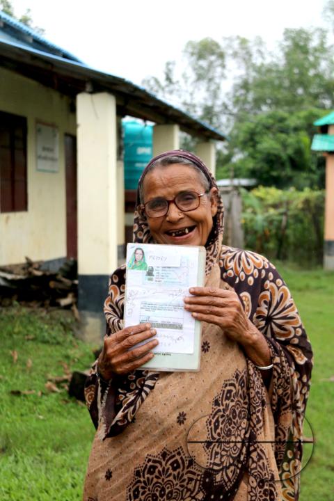 Portrait of a rural Bangladeshi woman showing her accommodation and old age allowances which are donated by the government