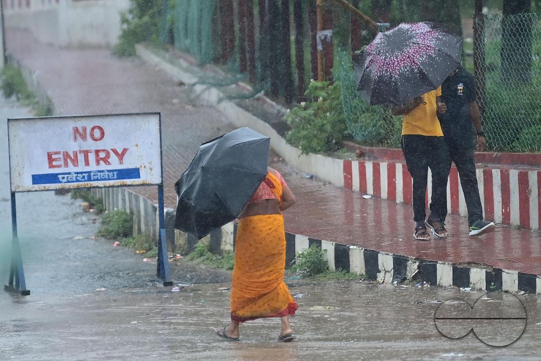 People crossing a deserted road in heavy rain during Cyclone Remal in Agartala