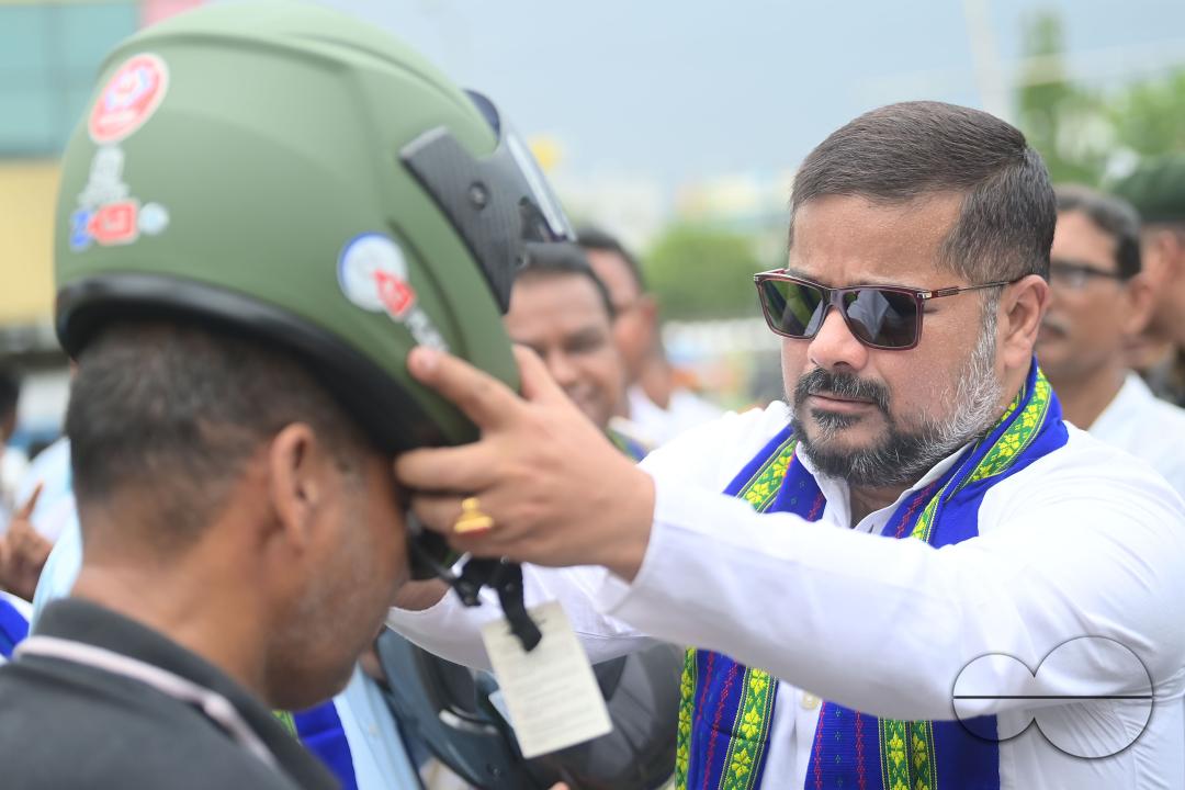 Transport Minister of Tripura, Sushanta Chowdhury puts a helmet on a motorist during a helmet distribution program and a road safety awareness campaign organised by the Tripura Transport Department at Agartala