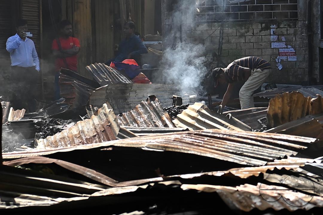 Shop owners and vendors are seen in front of their burnt shops and vegetables stalls in Battala market, the second biggest market in Tripura