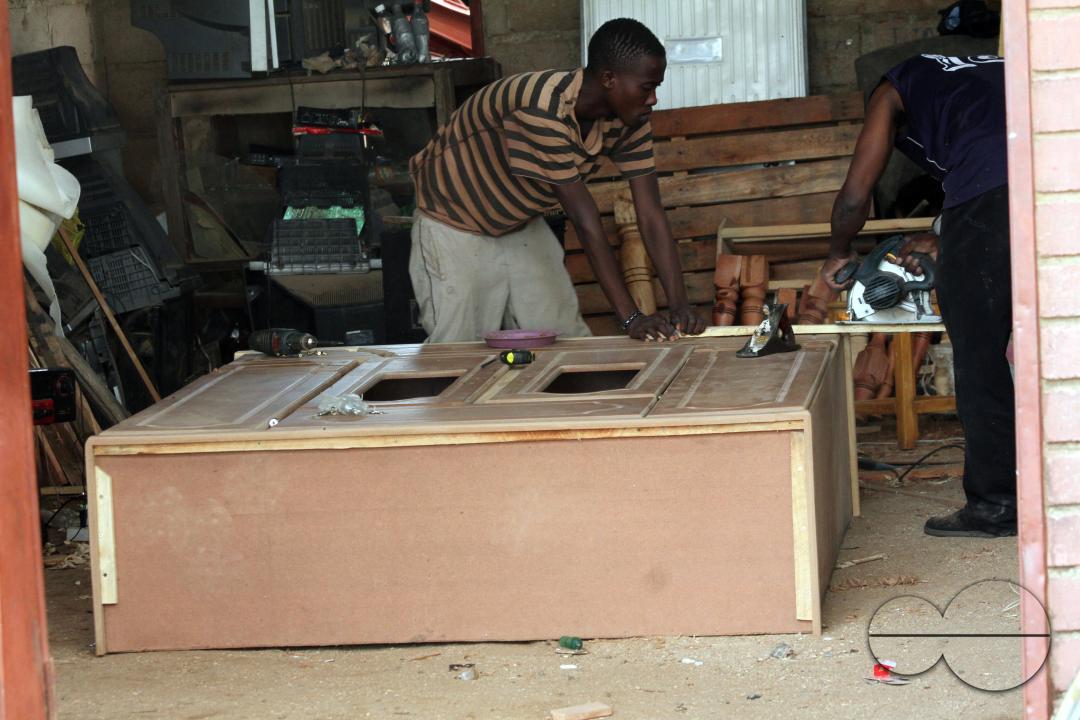 A carpenter making a wardrobe in his shop at a shopping centre in Mwenezi district, Zimbabwe.