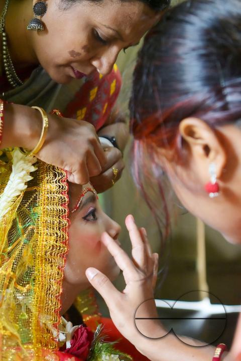 Devotees prepare the nine-year, five-month, and fourteen-day-old Hindu girl Debalina Chakraborty, known as a "Kumari," as she yawns while awaiting worship by priests during Durga Puja at the Ramakrishna Vivekananda Ashram