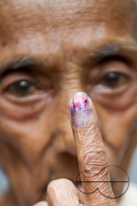 A 101-year-old woman shows her ink-marked finger after casting her vote through a postal ballot at her home in Agartala, in the presence of election officials and security personnel