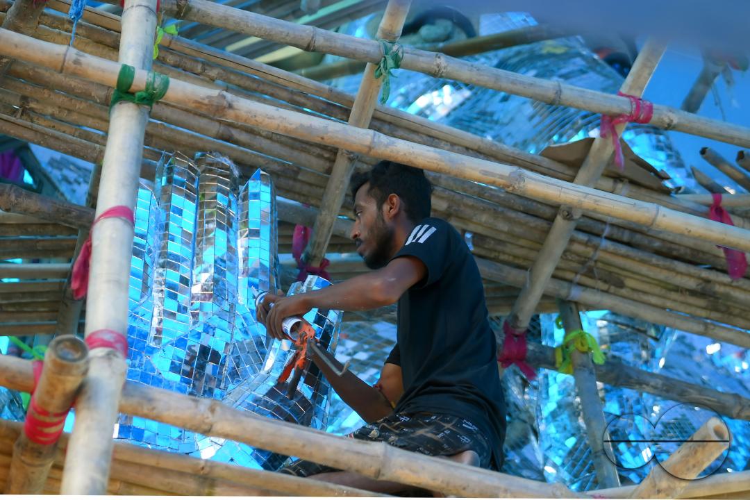 An artist is pasting glass pieces to make a 41 feet tall Ganesh idol, fully covered by glass, ahead of Ganesh Chaturthi festival in a pandal in Ranir bazar