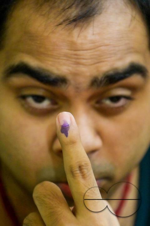 A differently abled boy shows his ink marked finger before casting his postal ballot vote with the assistance of her family members at her house in front of the team of election officials and security personnel in Agartala