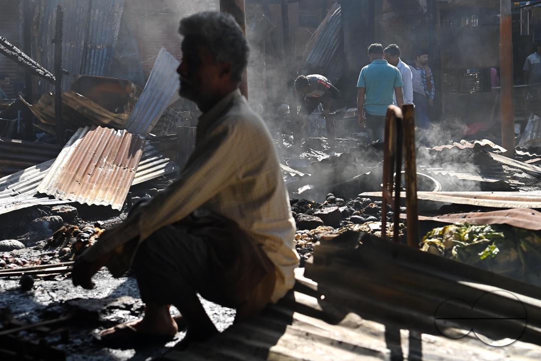 Shop owners and vendors are seen in front of their burnt shops and vegetables stalls in Battala market, the second biggest market in Tripura
