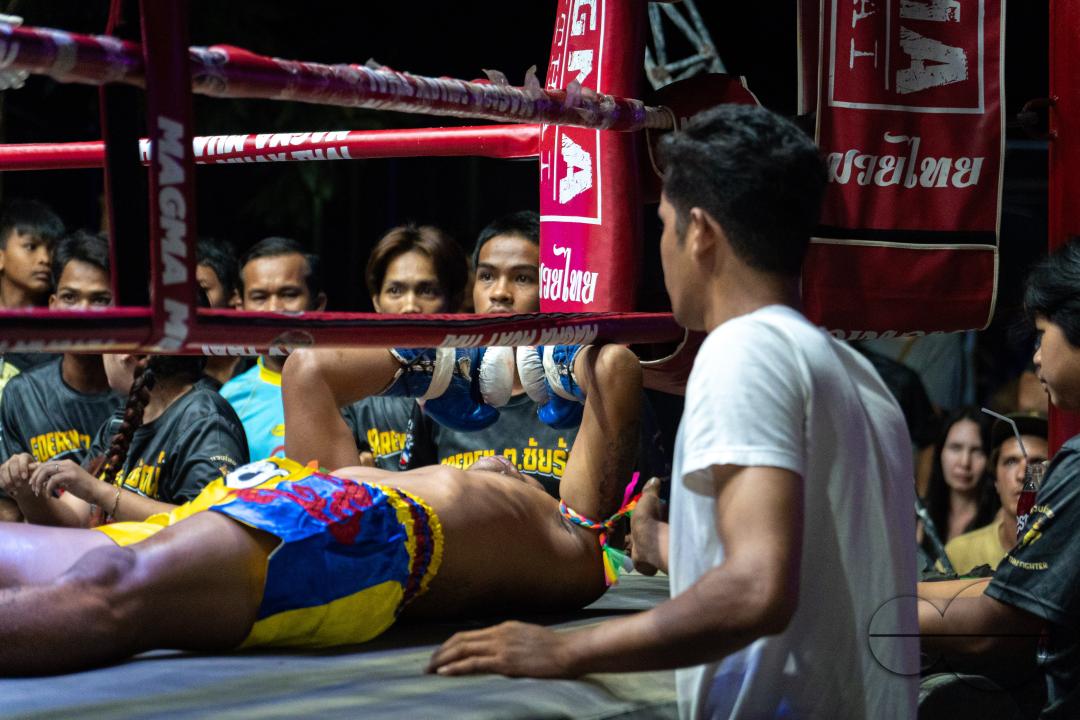 The Thai boxer Petch Si Nel, at the center, is seen lying on the ground after a knockout, watched by the audience, during the Muay Thai Fights, on Koh Chang Island, Thailand.