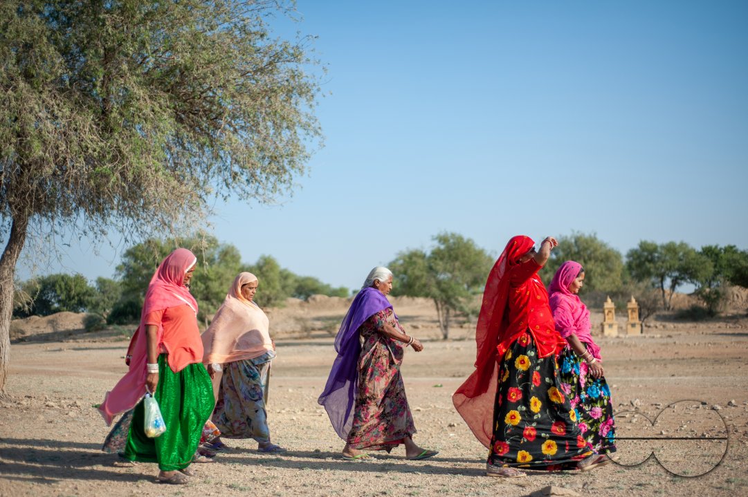 Women walk across an arid field on the outskirts of Jaisalmer.