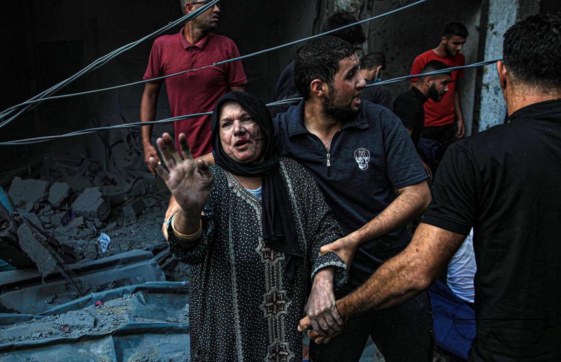 A man helps a Palestinian woman who is bady injured due to Israeli raids in Gaza City