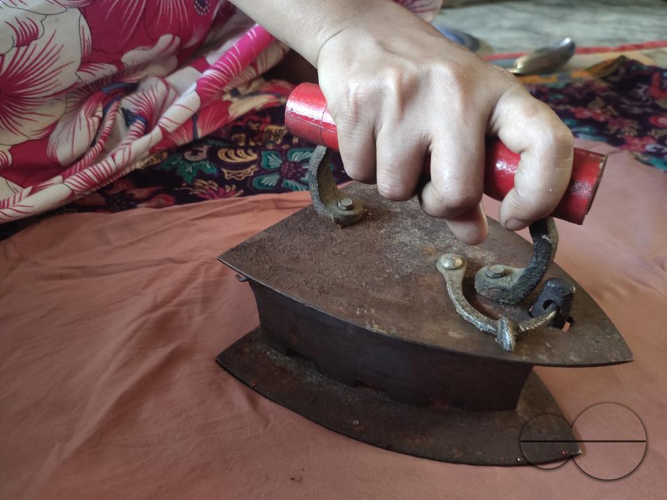A woman ironing with an old fashioned charcoal iron at the Balukhali refugee camp