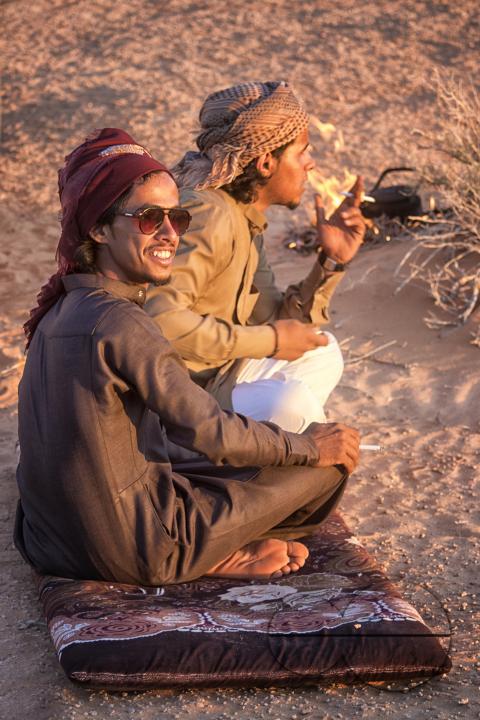 Two male bedouins sitting and smoking in the desert of Wadi Rum