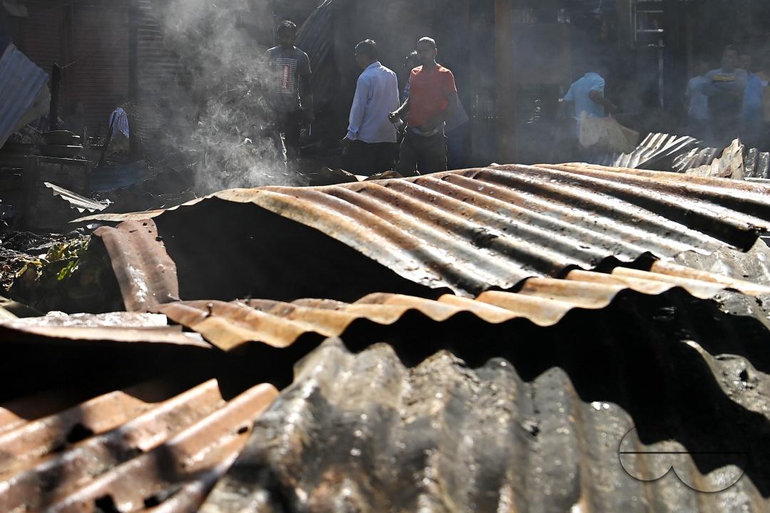 Shop owners and vendors are seen in front of their burnt shops and vegetables stalls in Battala market, the second biggest market in Tripura