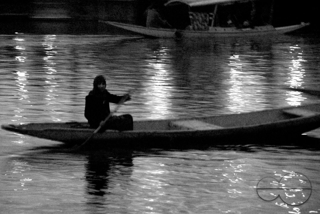 A Kashmiri boy rows across the Dal Lake at dusk.
