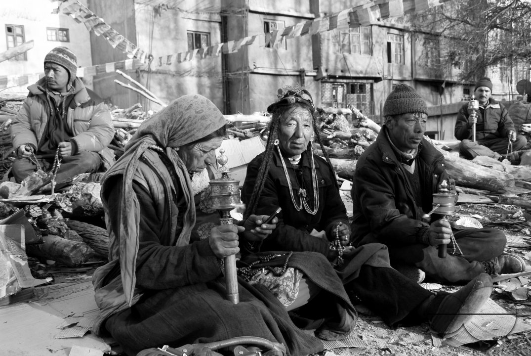Men and women sitting near a Temple with prayer wheels and beads in Leh, Ladakh.