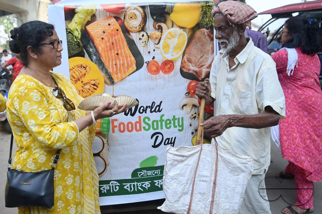 People get food from a social worker on World Food Safety Day, organised by "Roti Bank Foundation", in Agartala
