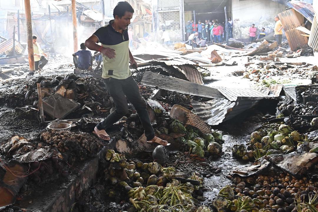 Shop owners and vendors are seen in front of their burnt shops and vegetables stalls in Battala market, the second biggest market in Tripura