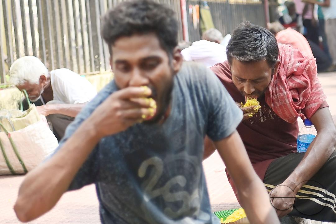 People eating food distributed by a social worker on World Food Safety Day organised by "Roti Bak Foundation", in Agartala