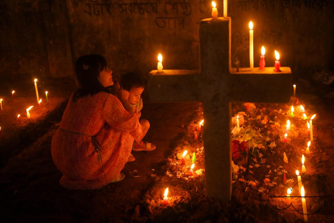 Christians offer prayers next to the graves of their family members at a cemetery during "All Souls Day" on the outskirts of Agartala