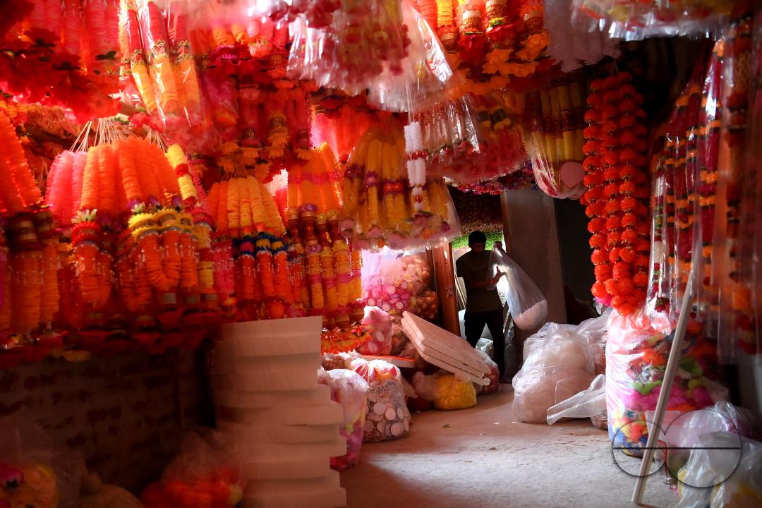 A worker arranging plastic garlands for sale at a stall ahead of the festive