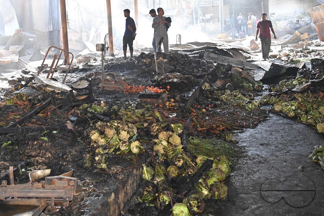 Shop owners and vendors are seen in front of their burnt shops and vegetables stalls in Battala market, the second biggest market in Tripura