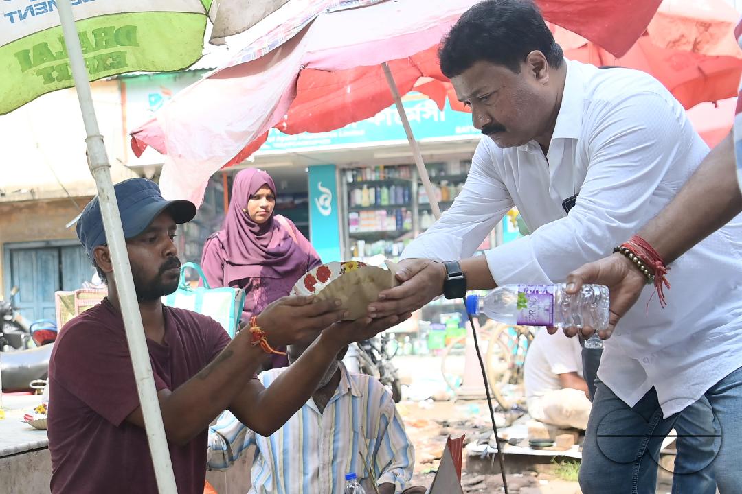 People get food from a social worker on World Food Safety Day, organised by "Roti Bank Foundation", in Agartala