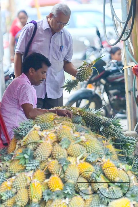 A vendor in Agartala sells fresh pineapples, a renowned summer fruit from Tripura, at a bustling roadside fruit market