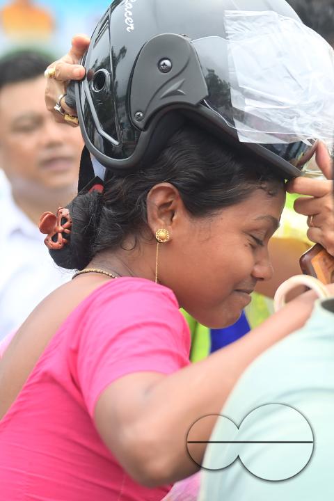 A traffic official puts a helmet on a motorist during a helmet distribution program and a road safety awareness campaign organised by the Tripura Transport Department at Agartala