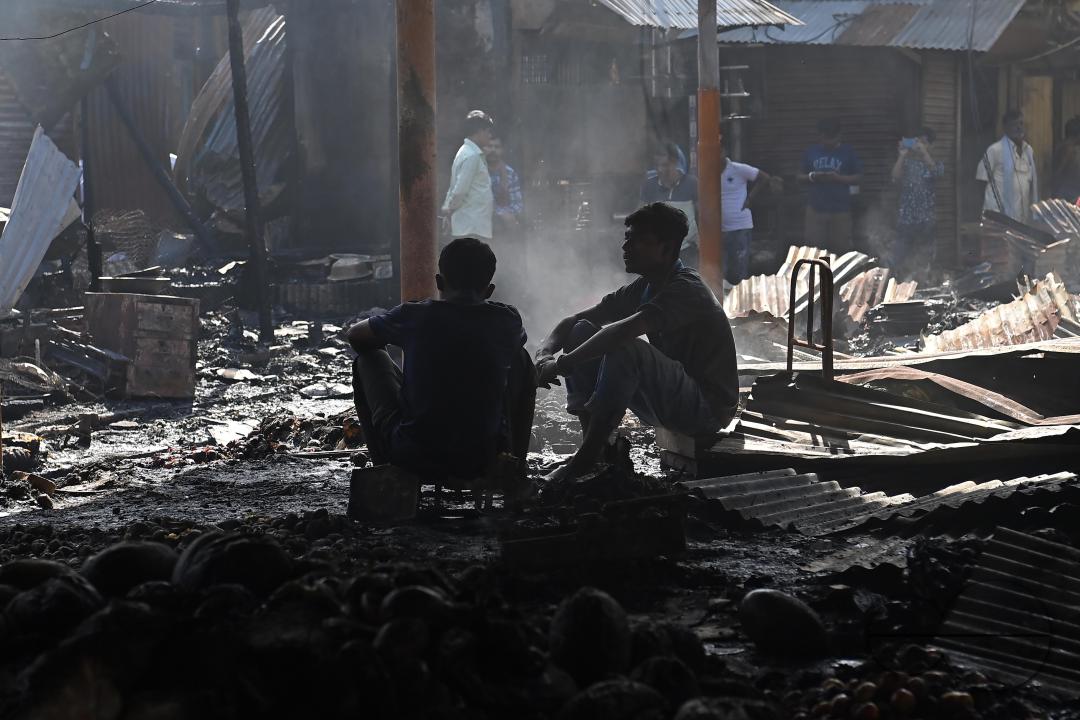 Shop owners and vendors are seen in front of their burnt shops and vegetables stalls in Battala market, the second biggest market in Tripura