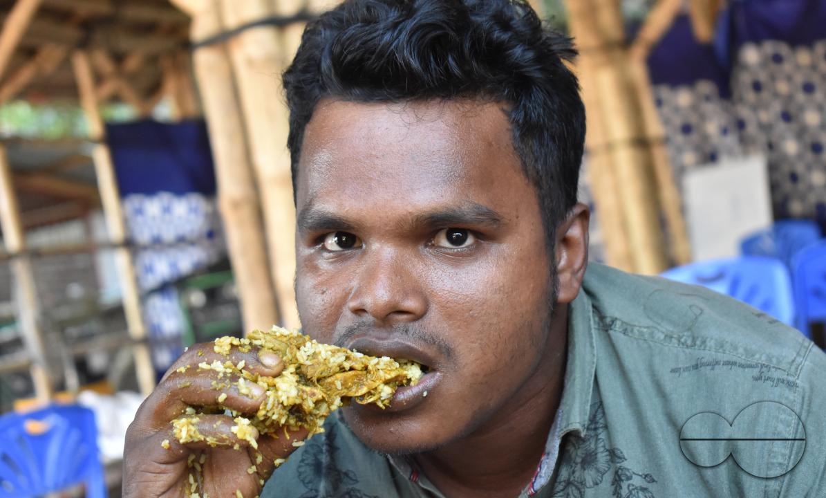 Portrait of a man eating chicken at the Balukhali refugee camp