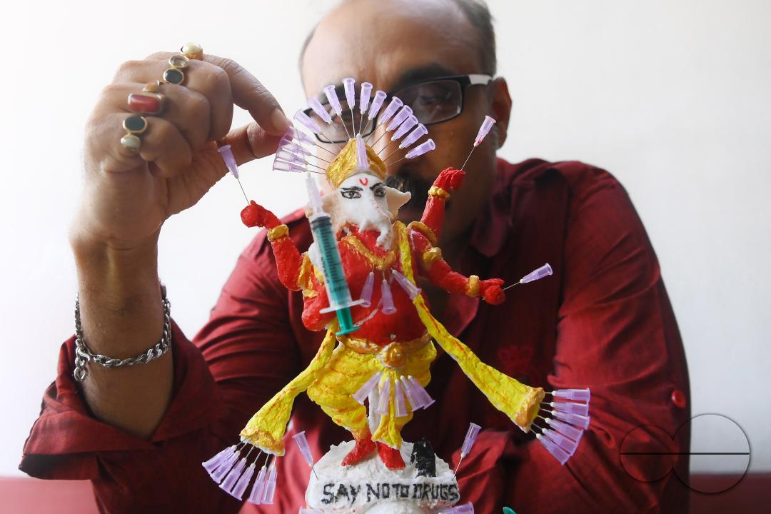 Samiran De, an artist works on an idol of Lord Ganesha made with soup and syringe needles to alert people against drugs, ahead of Ganesh Chaturthi festival, in Agartala
