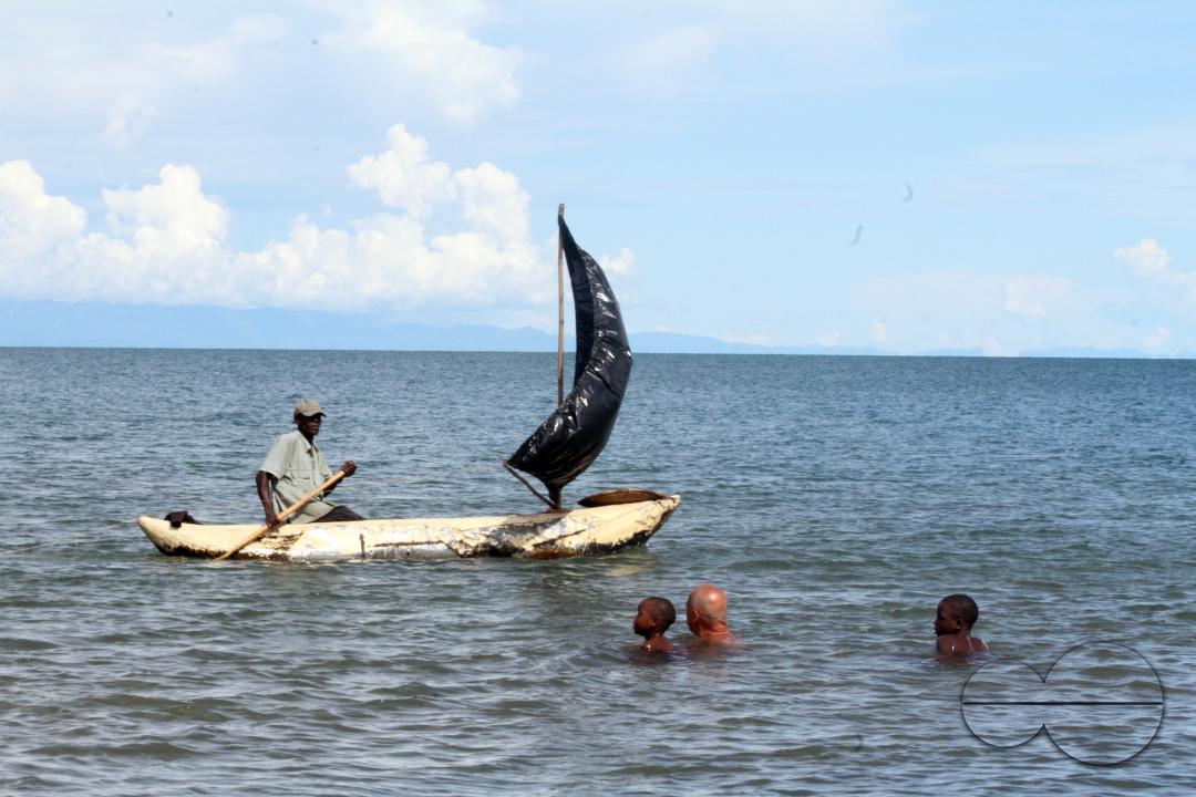 A fisherman on his canoe close to some swimmers on Lake Malawi, Senga Bay