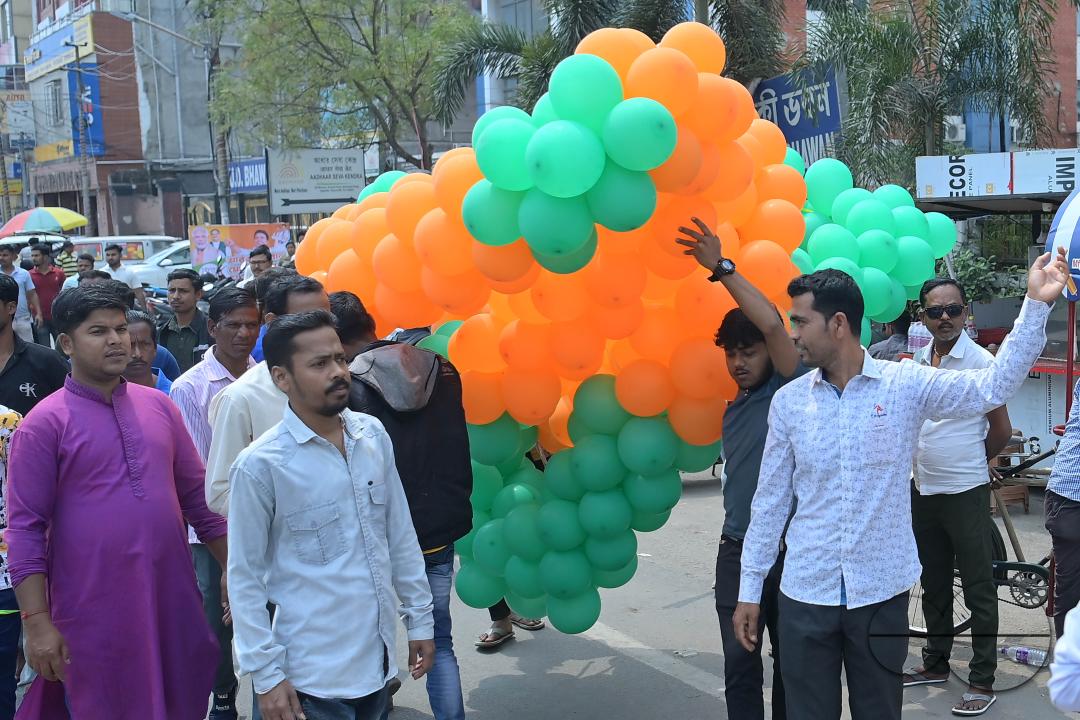 Supporters of the BJP are seen decorating balloons in the party's colours at a rally featuring Tripura Chief Minister Manik Saha, former CM and BJP candidate Biplab Kumar Deb, and Kriti Singh, alongside other leaders, during an election campaign rally in