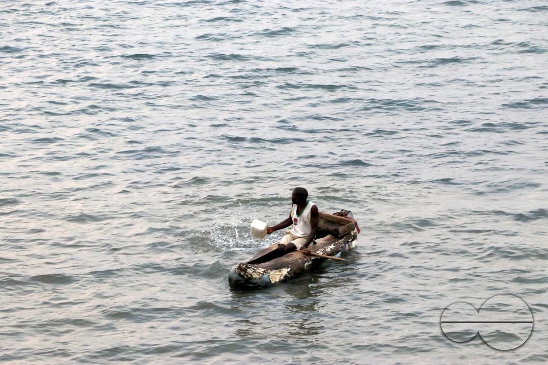 A fisherman is seen scooping out water from his leaking canoe on Lake Malawi